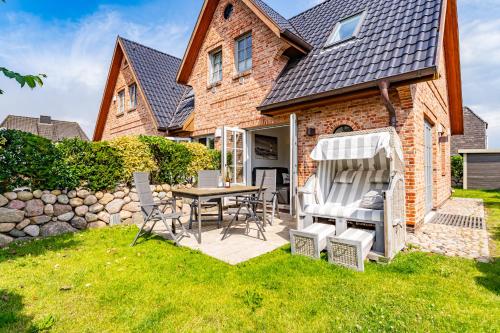 a house with a patio with a table and chairs at Am Luv in Tinnum
