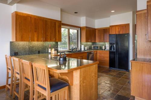 a kitchen with a black refrigerator and wooden cabinets at Elegant Water View, Walk To Moran State Park in Eastsound