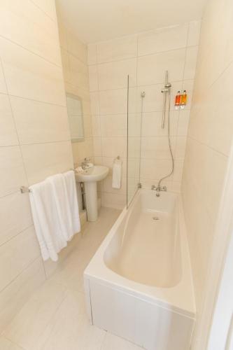 a white bathroom with a tub and a sink at Verve Hotel in Bedford
