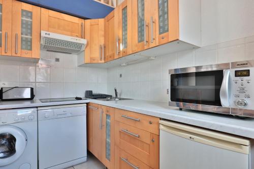 a kitchen with wooden cabinets and a microwave at Hôtel & Appart-hôtel Olatua in Bidart