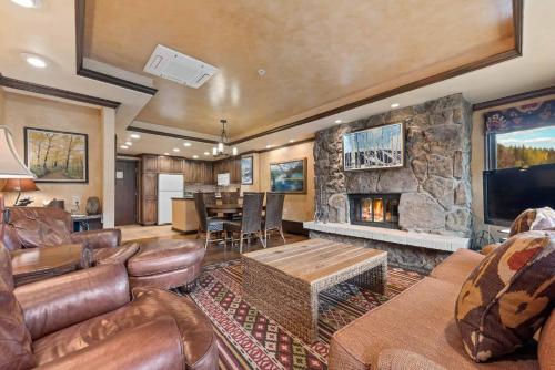 a living room with a stone fireplace and leather furniture at Lodge Tower 494 Two Bedroom Residence in Vail