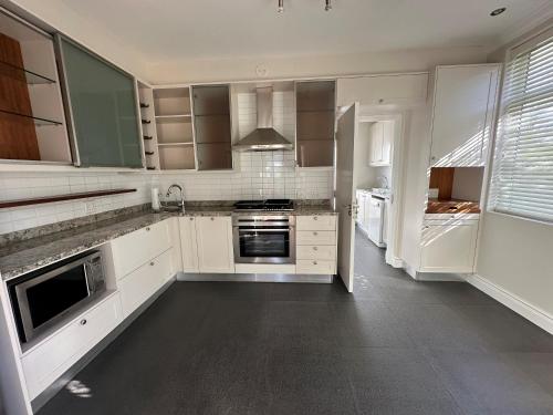 a kitchen with white cabinets and stainless steel appliances at Wild Mushroom Country House in Stellenbosch