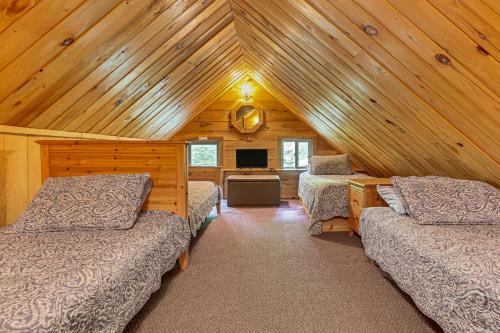 a bedroom with three beds in a wooden cabin at Less Than 8 Mi to Gore Mountain! Family Cottage with Porch in Bakers Mills