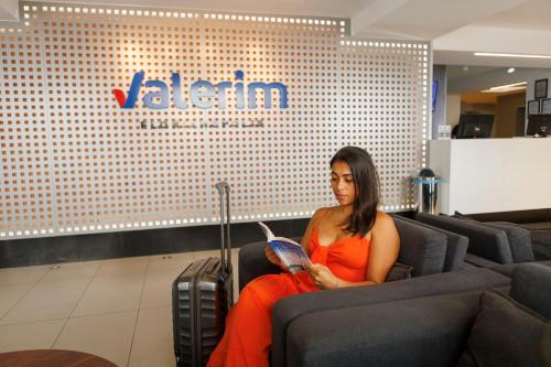 a woman sitting in a chair reading a book at Valerim Florianópolis in Florianópolis