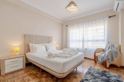 een slaapkamer met een groot wit bed met een raam bij White Charm by the Sea in Viana do Castelo