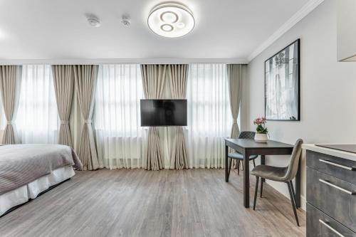 a bedroom with a bed and a desk and a television at Cleveland Residences Bloomsbury in London