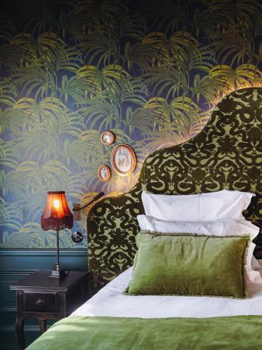 a bedroom with a bed with a green pillow and a wallpaper at Madame C - Hôtel très particulier in Strasbourg