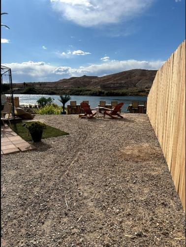 a wooden fence with chairs and a table next to a lake at Elegant Fishers Riverfront Paradise Private Beach in Bullhead City