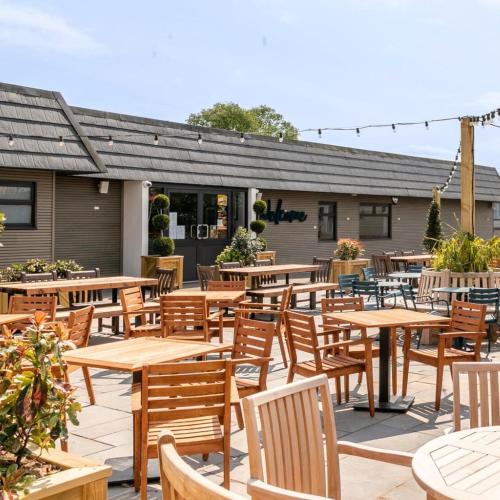 an outdoor patio with wooden tables and chairs at Carlisle Cabin in Port Carlisle