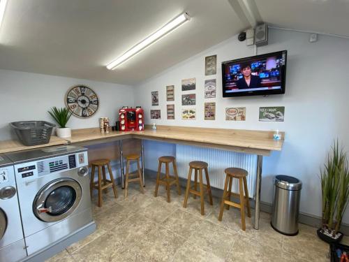 a kitchen with a bar with stools and a tv at Carlisle Cabin in Port Carlisle