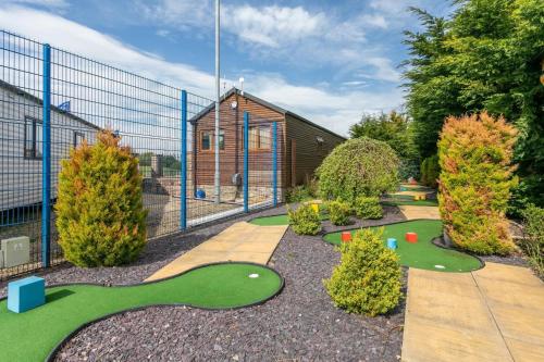 a miniature golf course in a garden with a building at Carlisle Cabin in Port Carlisle