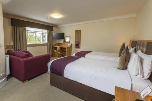a hotel room with two beds and a purple couch at Buchanan Arms Hotel & Leisure, Sure Hotel Collection in Drymen