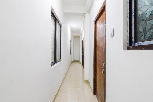 コルカタにあるHOTEL O SPの白い壁と木製のドアのある廊下