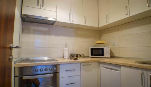 a kitchen with white cabinets and a sink and a microwave at Luxury Budva Center Apartments in Budva
