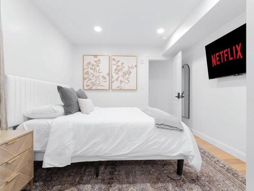 a white bedroom with a white bed and a tv at 4BR 3BATH Harvard MIT Home in Cambridge