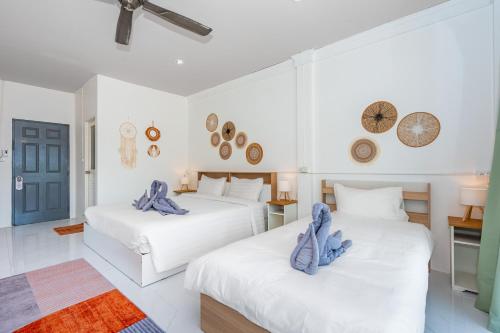 two beds in a white room with blue pillows on them at Kata Hill Sea View Hotel in Kata Beach