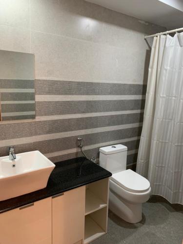 a bathroom with a white toilet and a sink at Lilly Ribera in Kumarakom