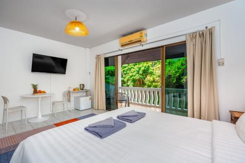 a bedroom with a white bed and a balcony at Kata Hill Sea View Hotel in Kata Beach