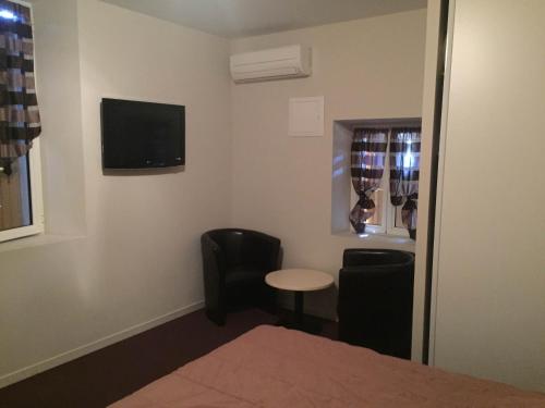 a room with two chairs and a table and a tv at Auberge Les Olivades in Mallemort
