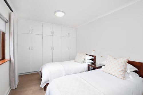 two beds in a room with white walls at Papillon in Stilbaai
