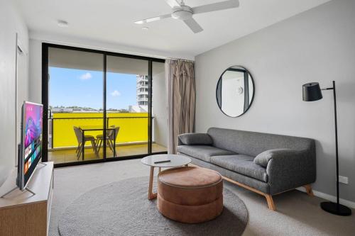 a living room with a couch and a tv and a table at 54Q Abnb-Style Apt Discover Riverside Bliss with Pool and Free Parking near Portside in Brisbane