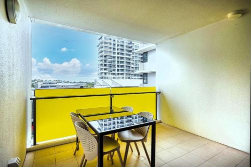 a balcony with a table and chairs and a yellow wall at 54Q Abnb-Style Apt Discover Riverside Bliss with Pool and Free Parking near Portside in Brisbane