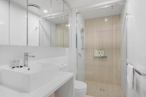 a white bathroom with a shower and a toilet at 54Q Abnb-Style Apt Discover Riverside Bliss with Pool and Free Parking near Portside in Brisbane