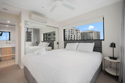 a white bedroom with a large bed and a bathroom at 54Q Abnb-Style Apt Discover Riverside Bliss with Pool and Free Parking near Portside in Brisbane