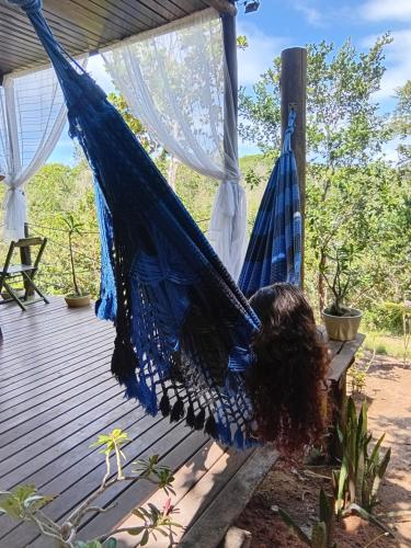 a woman laying in a hammock on a deck at Casa Contêiner imersão com Natureza Floresta Sapiranga-5km praia do forte in Mata de Sao Joao