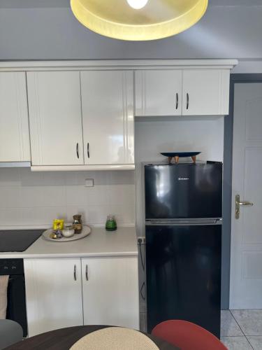 a kitchen with a black refrigerator and white cabinets at Lara3 in Kavala