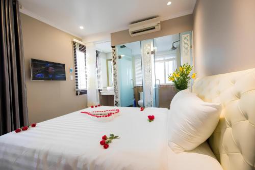 a bedroom with a white bed with red flowers on it at Little Hanoi Hotel in Hanoi