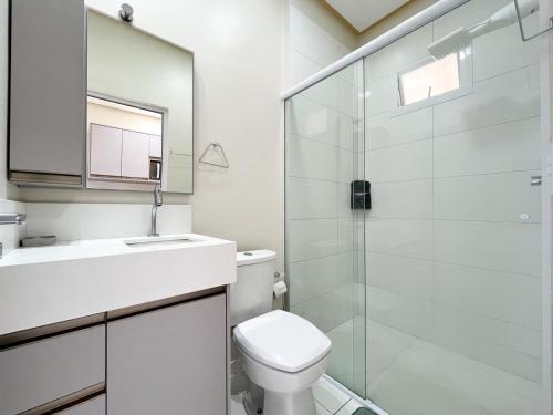 a bathroom with a toilet and a glass shower at Loft Sol e Mar Exclusivo em Bombinhas 50m da praia in Bombinhas