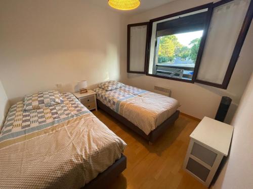 une chambre avec deux lits et une fenêtre dans l'établissement Appartement 2 chambres presqu'île du Cap-Ferret, à Lège-Cap-Ferret
