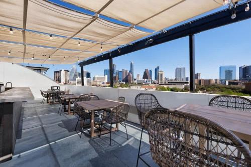 a rooftop patio with tables and chairs and a view of the city at Boulevard Stays Walk to Downtown 1BR SoCo Pool Parking Gym 01 in Austin