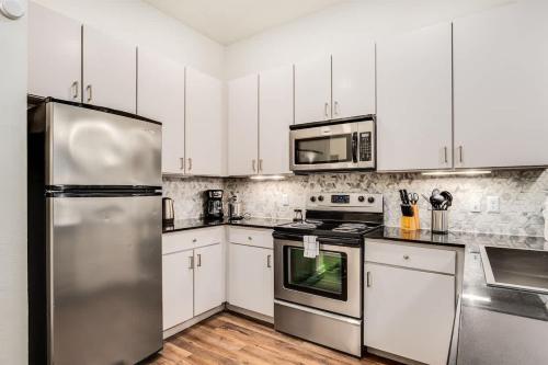 a kitchen with white cabinets and a stainless steel refrigerator at Boulevard Stays Walk to Downtown 1BR SoCo Pool Parking Gym 01 in Austin