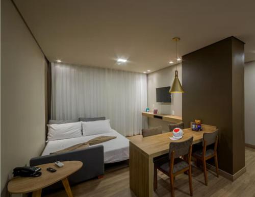 a bedroom with a bed and a table and a desk at Quarto no Laghetto Golden Resort in Gramado