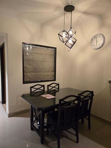a dining room with a table and chairs and a clock at Aloha Apartments by blissful Ganges in Rishīkesh