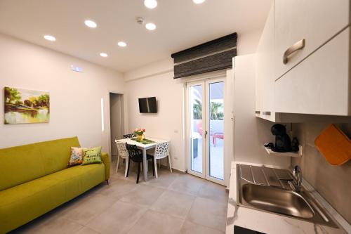 a living room with a green couch and a table at Dimora Domitia - Apartments in Mondragone