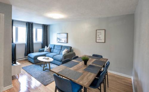 a living room with a table and a blue couch at 3BR 6Beds 5min Walk Metro Free Parking Place Bell in Laval