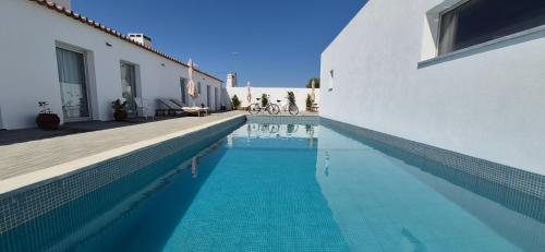 a swimming pool next to a white building with a house at Casas de Sao Miguel in Évora