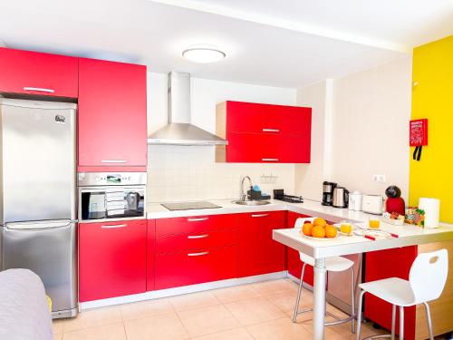 a kitchen with red cabinets and a table with oranges on it at Little Palmar with Free Parking & Pool & Padel in Palm-Mar