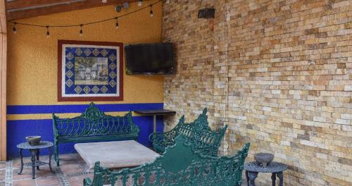 a patio with two green benches and a tv at Hotel Benedicta in Mexico City