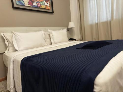 a bedroom with a bed with a blue and white blanket at Camaçari Plaza Hotel in Camaçari