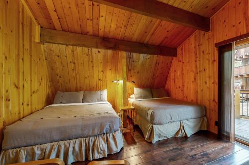 two beds in a room with wooden walls at Primrose Cabin #709 in Big Bear Lake