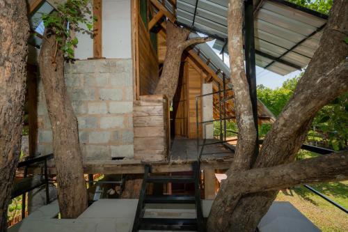 a treehouse in a forest with stairs in the middle at Wisdom Bungalow- Habarana in Moragaswewa