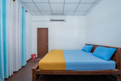 a bedroom with a bed with blue and yellow sheets at Wisdom Bungalow- Habarana in Moragaswewa