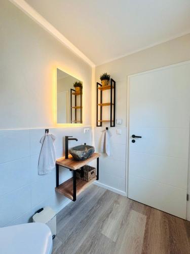 a bathroom with a sink and a mirror and a door at Ferienhaus zum See Sonnenglanz in Funfseen