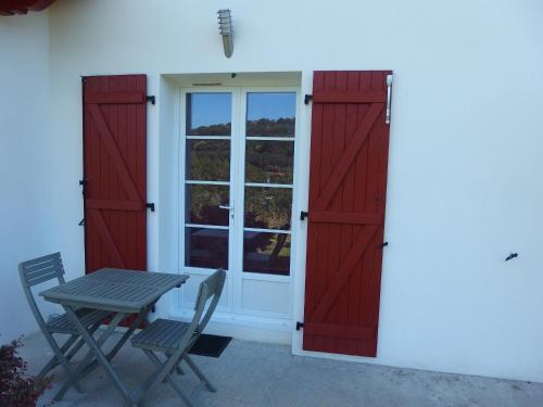 a table and chairs next to a building with red doors at Errobi Alde in Cambo-les-Bains