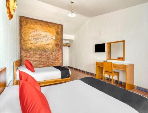 a hotel room with two beds and a desk at Hotel Arana Tonalá in Guadalajara
