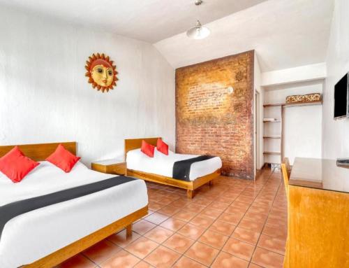 a hotel room with two beds and a television at Hotel Arana Tonalá in Guadalajara